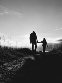 Rear view of silhouette people walking on field