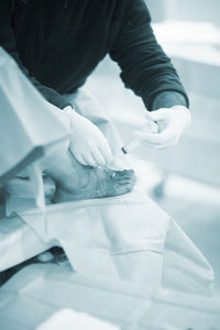 Midsection of doctor injecting syringe on patient foot in operating room