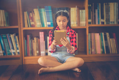 Girl using digital tablet while sitting in library