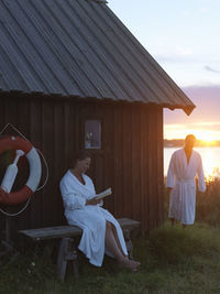 Couple near wooden house at sunset