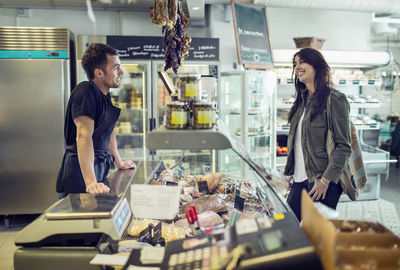 Side view of salesman attending female customer in supermarket