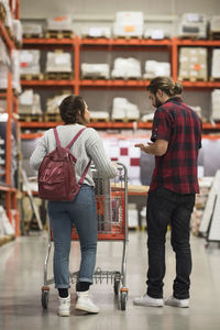 Full length rear view of couple discussing while walking in hardware store