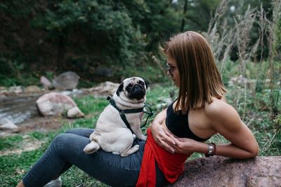 Rear view of woman with dog sitting outdoors