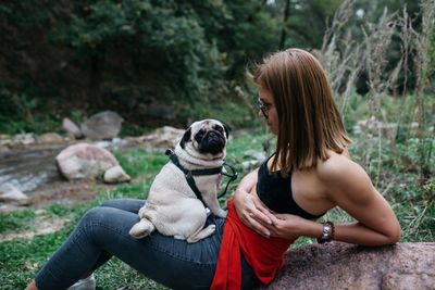 Rear view of woman with dog sitting outdoors