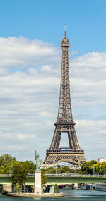 Eiffel tower against cloudy sky in city