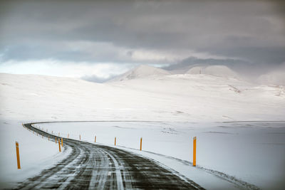 Road leading towards snowcapped mountains against sky