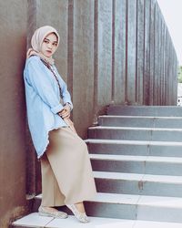 Portrait of woman wearing headscarf while leaning wall