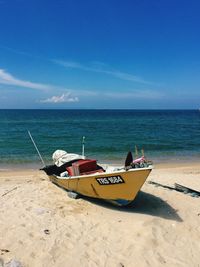 Boat moored at beach against sky