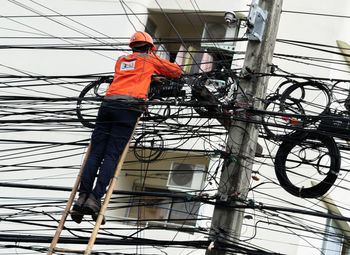 Low angle view of man working on cable