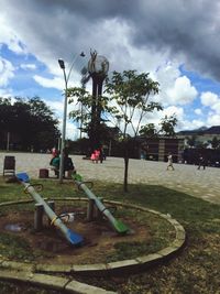 Trees in park against cloudy sky