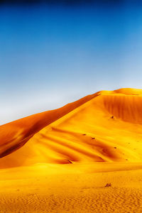 Scenic view of desert against clear blue sky