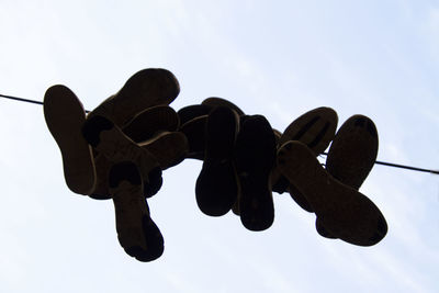 Low angle view of silhouette hanging against sky
