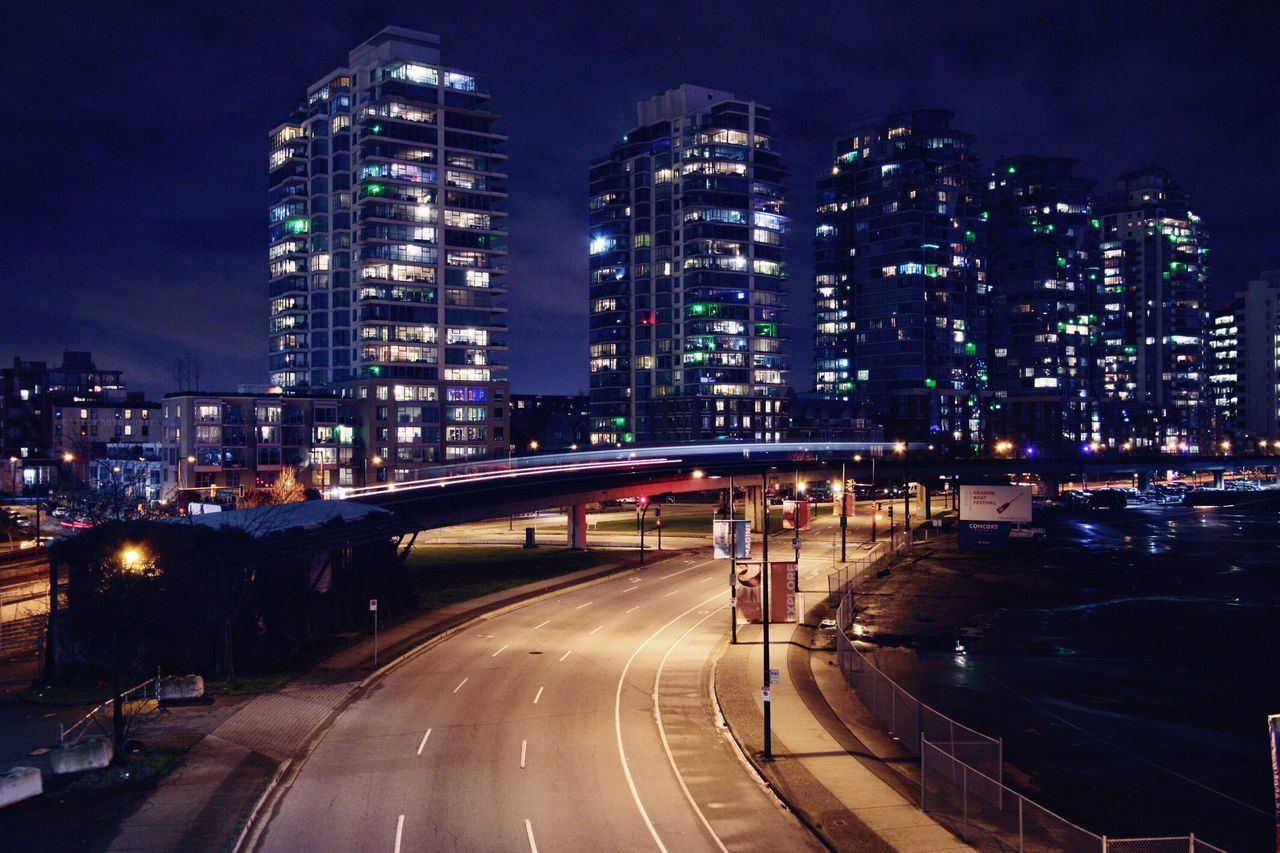 illuminated, night, building exterior, city, architecture, built structure, skyscraper, cityscape, tall - high, city life, road, modern, office building, city street, sky, capital cities, the way forward, building, travel destinations, outdoors, light trail, financial district, urban skyline, no people, tall, residential district, dark