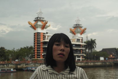 Portrait of young woman by river in city