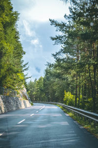 Road amidst trees in forest against sky