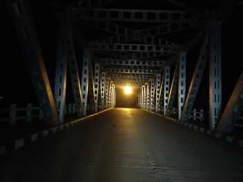 Empty road along footbridge at night