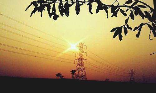 Low angle view of power lines against sky at sunset