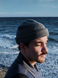 Close-up of young man wearing knit hat while standing at beach