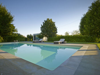 Swimming pool by trees against sky