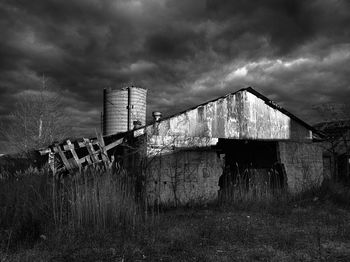 Low angle view of old abandoned house against cloudy sky