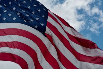 Low angle view of american flag against sky clouds red white blue