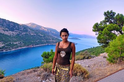 Portrait of woman standing against river by mountains