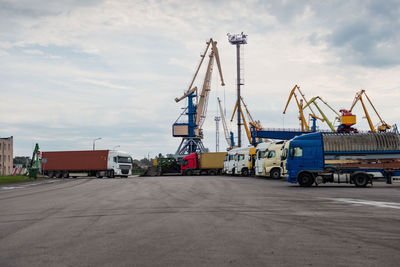 Cranes at harbor against sky