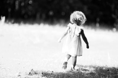 Rear view of girl walking on field