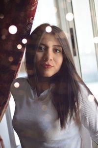 Portrait of young woman against window