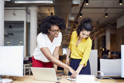 Businesswomen looking at documents while standing in office