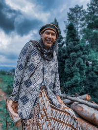 An old man with dreadlocks wearing a batik outfit.with a reggae hat.posing in front of the camera