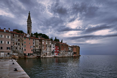 Buildings by sea against sky