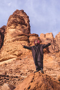 Full length of man with arms outstretched standing on rock formation