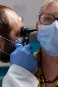 Portrait of doctor examining patients ear in clinic
