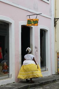 Rear view of woman against yellow building