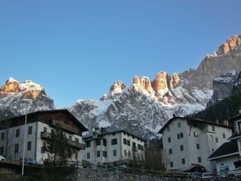 Buildings and mountains against clear blue sky