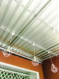 Low angle view of illuminated lighting equipment hanging on ceiling in building