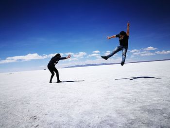 Optical illusion of woman throwing man on salt flat at salar de uyuni