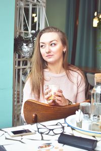 Portrait of young woman sitting at restaurant table