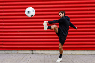 Man playing soccer ball on street