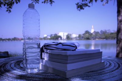 Close-up of bottle on table against calm blue lake