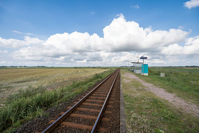 Railroad tracks on field against sky