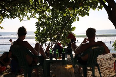 Rear view of people sitting on beach