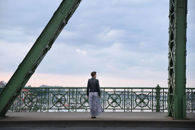 Rear view of woman standing by railing against sea