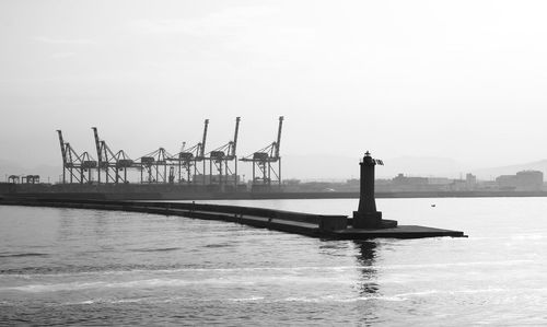 Cranes at commercial dock against sky