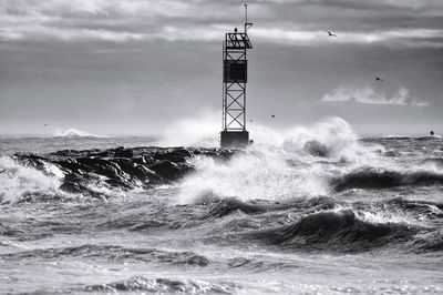 Lighthouse by sea against sky