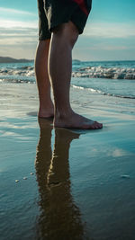 Low section of man standing on beach