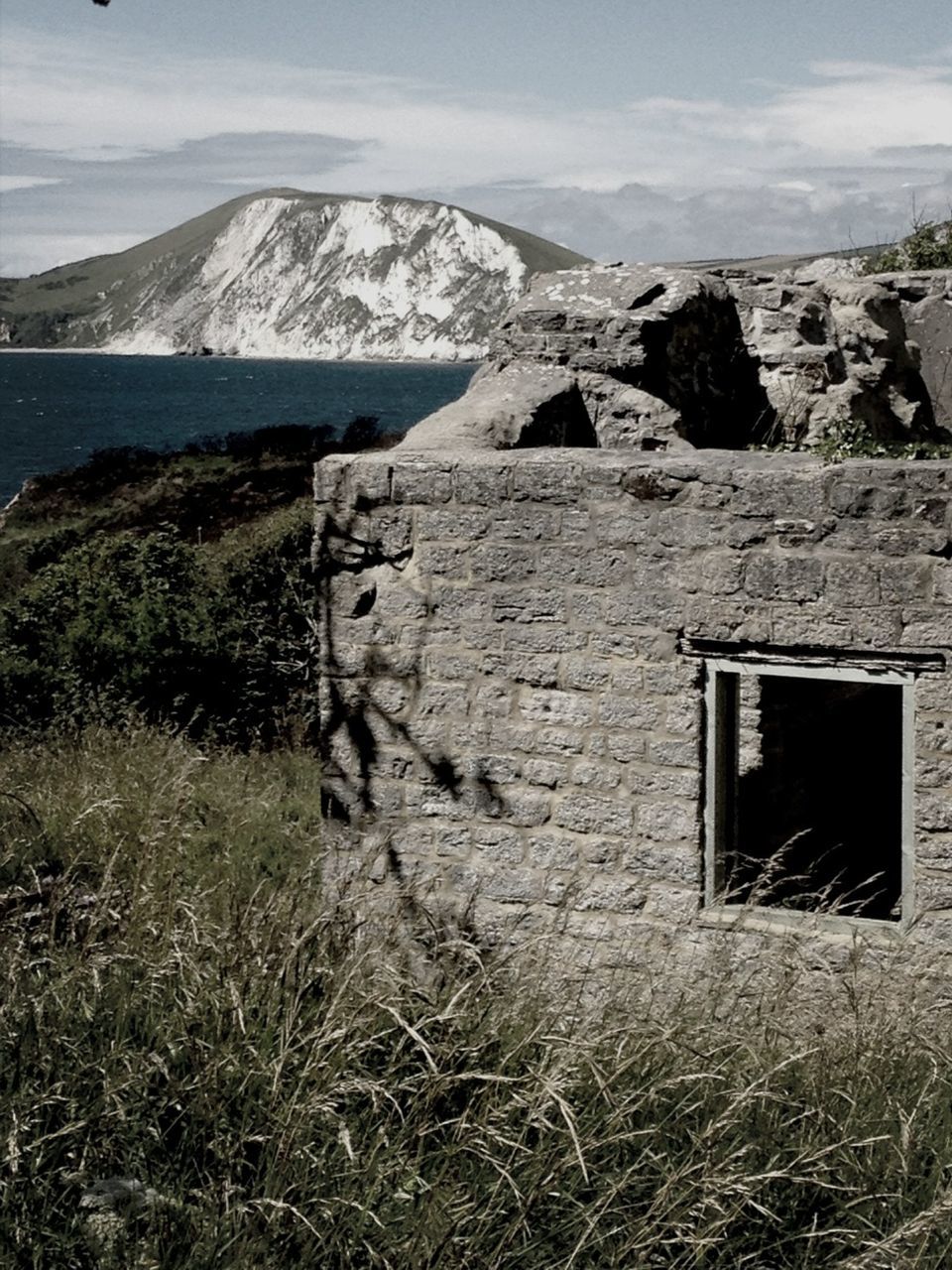 mountain, sky, built structure, grass, architecture, landscape, building exterior, tranquility, field, tranquil scene, nature, house, day, scenics, damaged, rock - object, abandoned, mountain range, old, no people