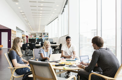 Young university friends studying together in library