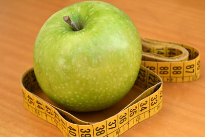 Close-up of granny smith apple with tape measure on table